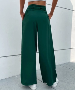 Rear view of dark green high-waisted wide-leg trousers showing drape and pocket detail