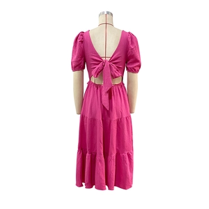 Detail of rose pink dress featuring a large bow tie, open back, and tiered skirt