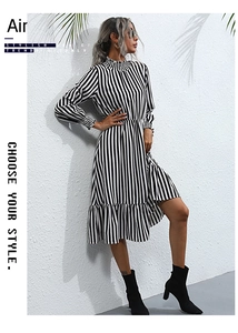 Close-up of black and white vertical striped dress showing ruffle cuffs and high neckline