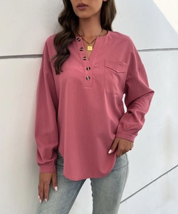 Detail of pink long sleeve shirt featuring wood texture buttons and front flap pocket