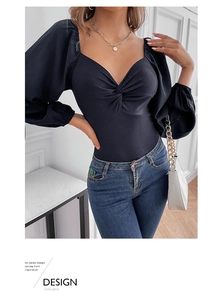 Detail of black long-sleeve bodysuit featuring a front twist knot and ribbed texture fabric