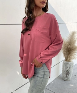 Detail of dusty pink long-sleeve blouse featuring textured fabric and front buttoned pocket