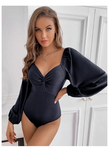 Detail of black bodysuit featuring elegant front knot design and textured ribbed fabric finish