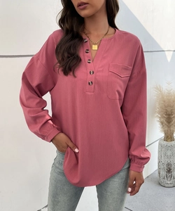 Detail showing the V-neckline with decorative buttons and chest pocket on long sleeve shirt