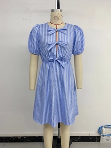 Détail de robe à rayures bleues et blanches avec manches bouffantes et nœuds décoratifs