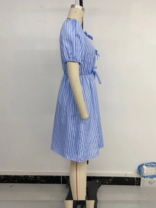 Détail de robe d'été à rayures bleues et blanches avec manches bouffantes et nœud