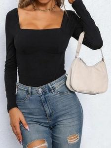 Detail eines schwarzen gerippten Bodysuits mit Karree-Ausschnitt und zerrissenen Jeans