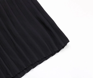 Dettaglio della trama in tessuto plissettato nero per un abito a maniche lunghe con scollo a V