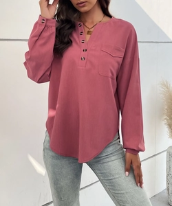 Detail of dark pink long-sleeve blouse featuring buttoned neckline and textured fabric