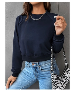 Detail of navy blue cropped crewneck sweatshirt with ribbed cuffs and gold necklace accent