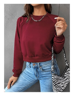 Close-up of burgundy crewneck cropped sweatshirt with ribbed hem and raglan sleeves