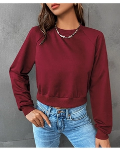Detail of burgundy cropped sweatshirt featuring raglan sleeves and ribbed cuffs on model
