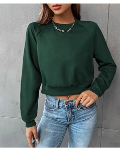Detail of dark green cropped sweatshirt with raglan sleeves and ribbed hem on a model