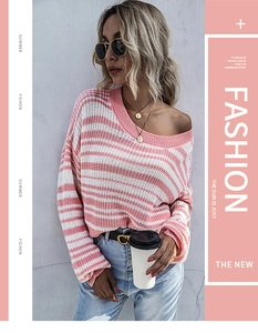Détail de la texture du pull rayé rose et blanc avec colliers de pièces d'or superposés