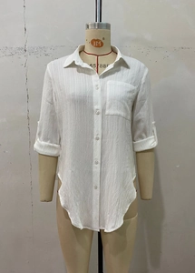 Detail of white long sleeve shirt with high side slits and textured fabric finish