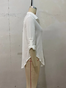 Detail of white textured long sleeve shirt showing fabric texture and roll-up sleeves