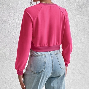 Back view of a rose red cropped sweatshirt with raglan sleeves and ribbed cuffs