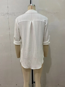 Detailed back view of a white blouse featuring vertical texture and inverted box pleat design