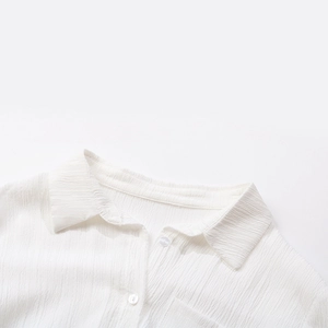 Close-up of white textured long sleeve shirt detailing the collar and pleated fabric