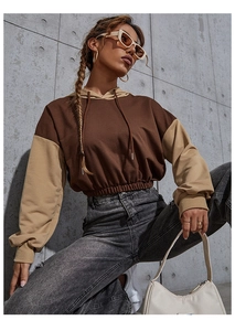 Detalle de sudadera corta con capucha bicolor con mangas en contraste marrón y crema