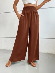 Detailed macro view of dark brown high-waisted wide-leg trousers with elastic waistband