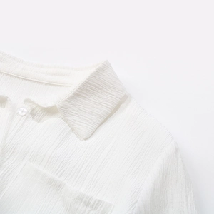 Close-up detail of white textured shirt with lapel collar and single chest pocket