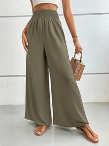 Detail of high waisted wide leg trousers in moss green with elastic smocked waistband