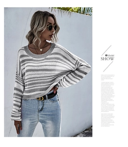 Détail d'un pull en tricot à rayures gris et blanc avec col rond et manches longues chic