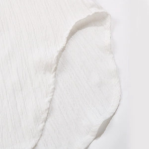 Detail shot of white textured seersucker fabric and neat curved hemline stitching
