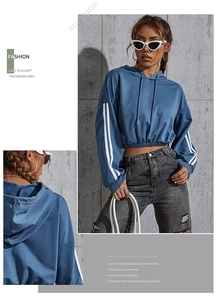 Detail of blue cropped hoodie featuring sporty white sleeve stripes and drawstring hem