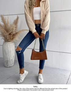 Vista completa giacca in pile beige da donna con crop top bianco e jeans denim strappati