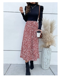 Detail of high neck black top with puff sleeves and red abstract pattern maxi skirt