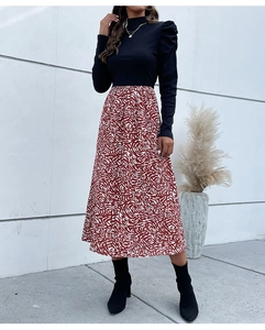Detail of high neck black puff sleeve knit top paired with red abstract pattern skirt