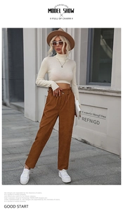 Detail of high waist corduroy pants with elastic paperbag waist and button in brown