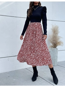 Detail of high neck black knit top with stylish puff sleeves and red swirl chiffon skirt