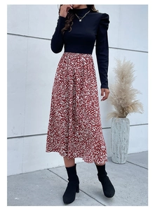 Detail of elegant black turtleneck top with puff sleeves and red pattern midi skirt