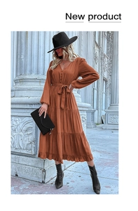 Detail of caramel V-neck dress featuring button accents and tiered pleated skirt hem