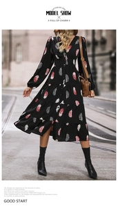 Détail d'une robe noire à manches longues avec motifs plumes, col en V et jupe à volants
