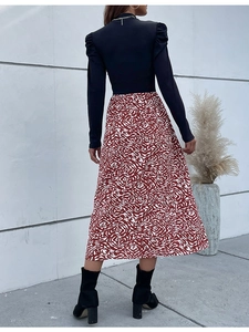 Detail of elegant black long sleeve mock neck top and red abstract print A-line skirt