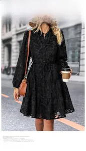 Detail of black tiered dress featuring floral jacquard texture and button-up waist tie