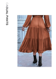 Detail of tiered ruffle hem on a brown long sleeve dress with elegant pleats and belt