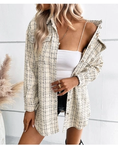 Detailed view of women's tweed plaid jacket featuring elegant pearl button accents