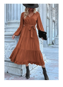 Detail of rust red tiered pleated dress featuring a V-neck and long sleeves on a model