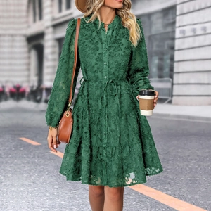 Detail of dark green dress showing textured 3D jacquard fabric and tiered skirt design