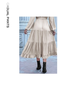 Detail of a beige long-sleeved tiered dress with ruffled layers and a flowing hemline