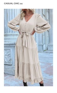 Detail of elegant beige long sleeve V-neck dress with layered ruffle skirt and waist tie