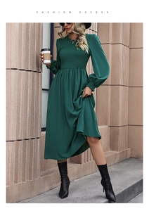 Close-up of smocking texture and elastic pleats on a dark green chiffon midi dress