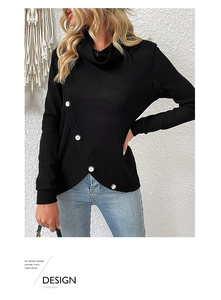 Detail of black knit top featuring diagonal white buttons and asymmetric V-shaped hem