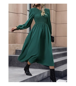 Detail view of dark green smocked waist dress with long lantern sleeves and pleated texture