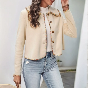 Detail of cream cardigan featuring colorful floral lace trim and brown buttons on the front